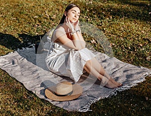 Girl with a straw hat in the spring in the park. Brunette with long hair on a background of summer nature. Youth and beauty