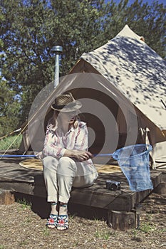 A girl in a striped shirt holds a butterfly net in front of a bell tent