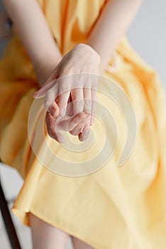 The girl strokes her hands. Beautiful female hands on a yellow background. Take care of your hands photo