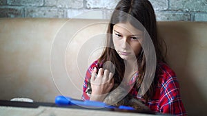 Girl stroking cat and watching tablet at home