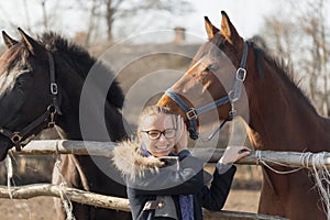 Girl stroking a thoroughbred horse in the pen for paddock
