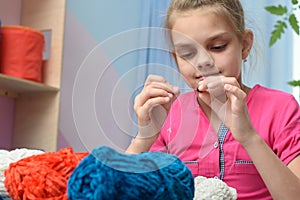 Girl strung a bead on a needle embroidering toys