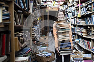 Girl student carries a large stack of books in the library, preparation for study, knowledge is power, concept