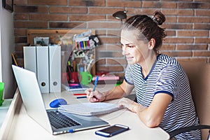 Girl student freelancer working with laptop at home by the window, education and remote work, programmer, online business