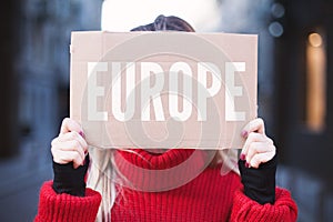 Girl student holding a sign with the inscription `Europe`. Hitchhiking around Europe.