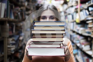 Girl student holds a stack of books in the library, she searches for literature and offers to read, a woman prepares for study,