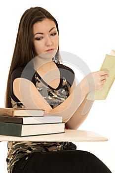 Girl student looking at pile of books on her desk