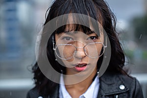 A girl student looks intently into the camera from under her glasses.