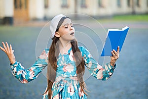 Girl student reading book outdoors, recite poetry concept