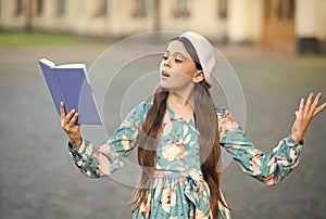 Girl student reading book outdoors, recite poetry concept photo