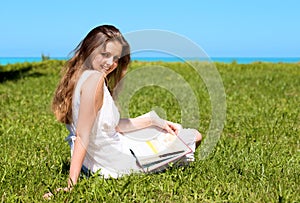 Girl-student sit on lawn and reads textbook