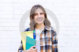 Girl student smiling on a background of a white brick wall.