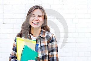 Girl student smiling on a background of a white brick wall.