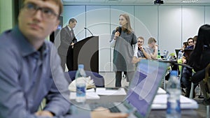 Girl student speaks at a seminar at the university using a microphone and the projector. Modern classroom instruction