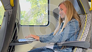 A girl student studies at a laptop while traveling on a train. Using a laptop while traveling