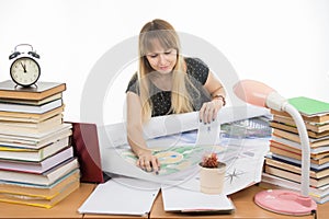 Girl student studying design drawing master plan at table cluttered with books