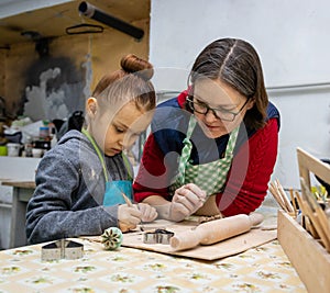Girl student talking with a female mentor in a ceramic workshop. Close up