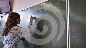 A girl student writes on the green board.