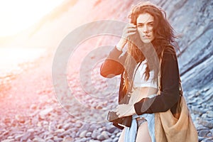 Girl in style of boho with a camera at sea in the rays of a bright sun