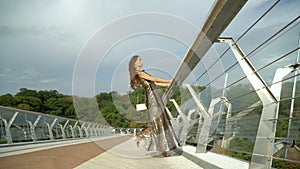 Girl in a stylish dress on the bridge in the city