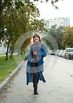 Girl in stylish hipster outfit running and having fun. Exiting emotions. Autumn mood. Wearing gray sweater. Fashion