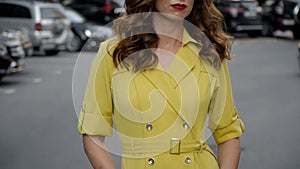 Girl in a stylish yellow dress posing in the parking lot. Camera wiring from bottom to top