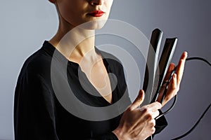 Girl stylist holding a Curling iron for hair. White isolated background