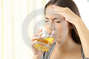 Girl suffering headache drinking a medicine