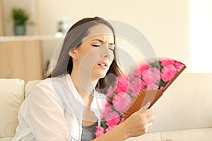 Girl suffering a heatstroke fanning at home photo