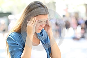 Girl suffering migraine in the street