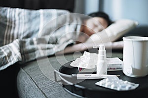 Girl suffering from a seasonal cold lies in bed. Antiviral drugs on a tray