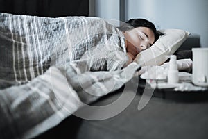 Girl suffering from a seasonal cold lies in bed. Antiviral drugs on a tray