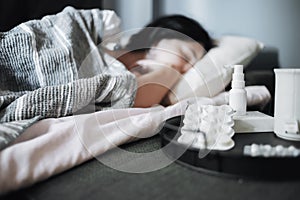 Girl suffering from a seasonal cold lies in bed. Antiviral drugs on a tray