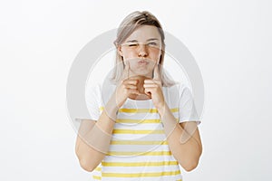 Girl suggest not to sulk but enjoy life. Portrait of carefree happy beautiful woman in striped t-shirt, pouting and photo