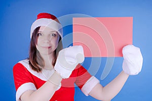 Girl in a suit `Santa Claus` with a sign on a blue background. The concept of discounts and sales for Christmas. Discount on holid