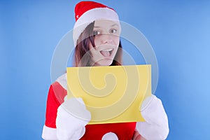 Girl in a suit `Santa Claus` with a sign on a blue background. The concept of discounts and sales for Christmas. Discount on holid