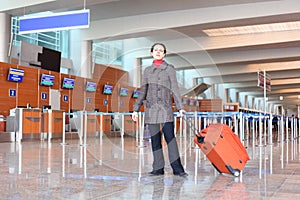 Girl with suitcase standing in airport hall