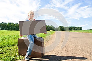 Girl with suitcase standing about road