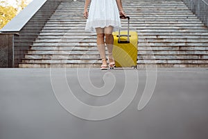 girl with a suitcase on the street. close-up of female legs and yellow suitcase.