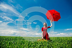 Girl with suitcase and umbrella at wheat field