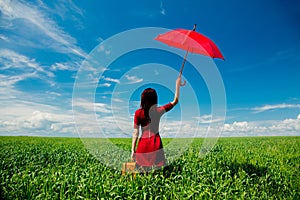 Girl with suitcase and umbrella at wheat field