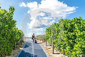 Girl with suitcase walking to the beach on Footpath. South Beach in Miami, Florida, USA