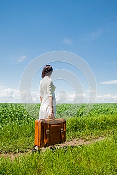Girl with suitcase at wheat field