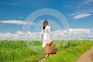 Girl with suitcase at wheat field