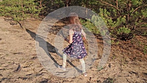 Girl in a summer dress runs in a pine forest