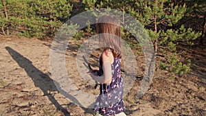 Girl in a summer dress runs in a pine forest