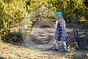 Girl in a summer dress runs in a pine forest