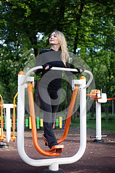 The girl on the summer sports ground does sports exercises on the stepper. Healthy lifestyle