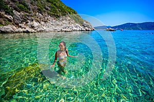 Girl with sun hat relaxing and swimming at Porto Timoni beach at Afionas is a paradise double beach with crystal clear azure water
