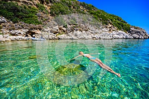 Girl with sun hat relaxing and swimming at Porto Timoni beach at Afionas is a paradise double beach with crystal clear azure water